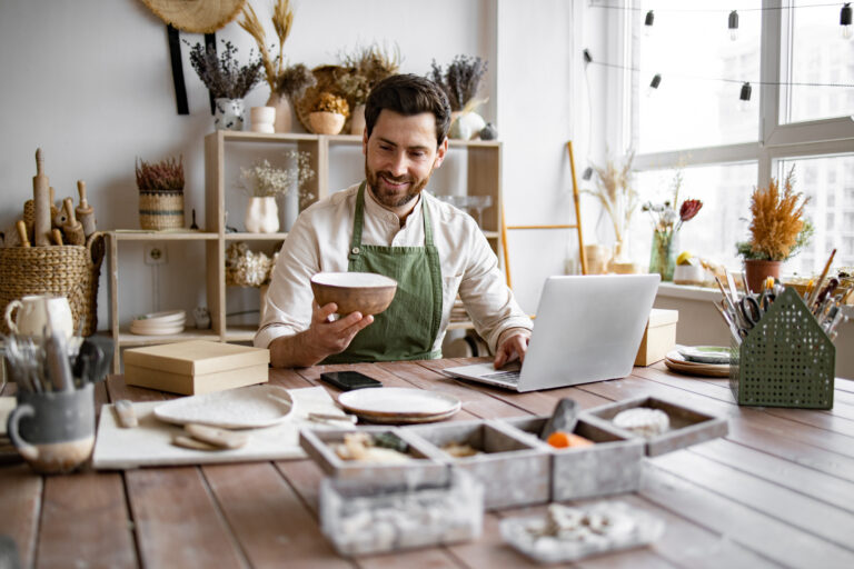 Artist working in his studio while filling orders through his computer